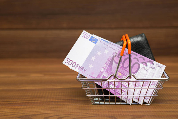 Panier avec euro et sac à main sur fond en bois. concept financier
 - Photo, image