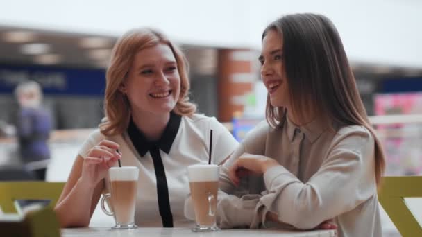 Dos mujeres jóvenes hablando y tomando café sentadas en la cafetería. - Metraje, vídeo