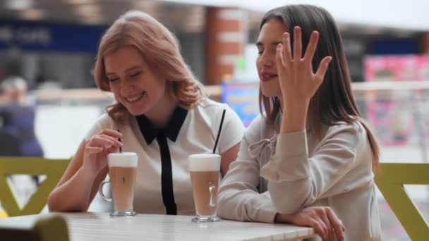 Due giovani donne che parlano e bevono caffè seduti nel caffè. - Filmati, video