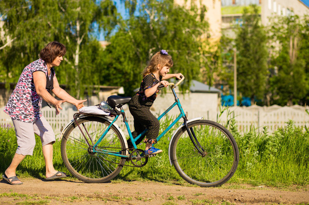 Grand-mère enseigne à sa petite-fille à monter un vieux gros vélo
 - Photo, image