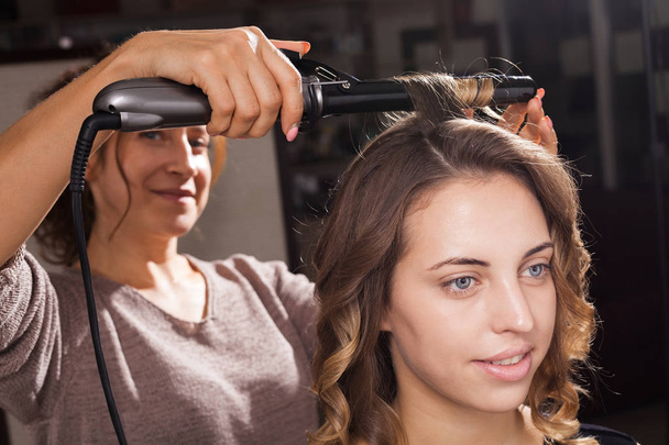pretty woman is having a hair curling - Фото, изображение