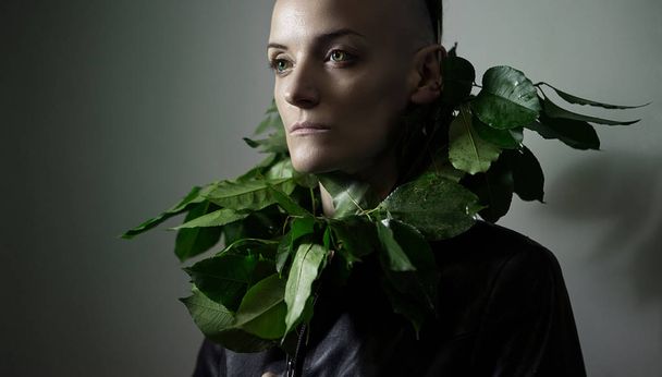 Portrait of an Elf Girl. Nature Protection. Model's Face with pale skin and green leaves near her face. Ecological concept, human and nature. Environmental Protection. Beautiful unusual girl model.  - Fotó, kép