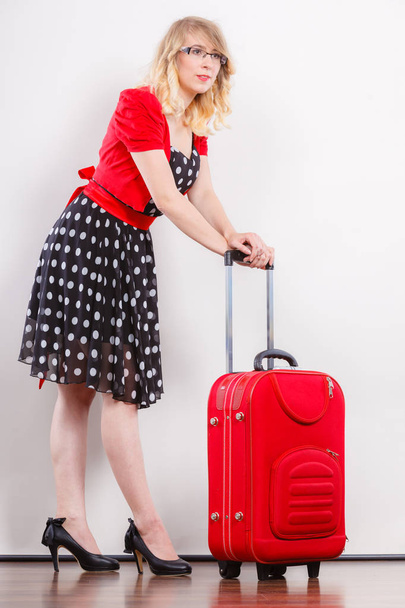 Traveling vacation concept. Elegant young woman in full length wearing polka dot black dress high heels with red suitcase ready for trip journey - Foto, Imagen