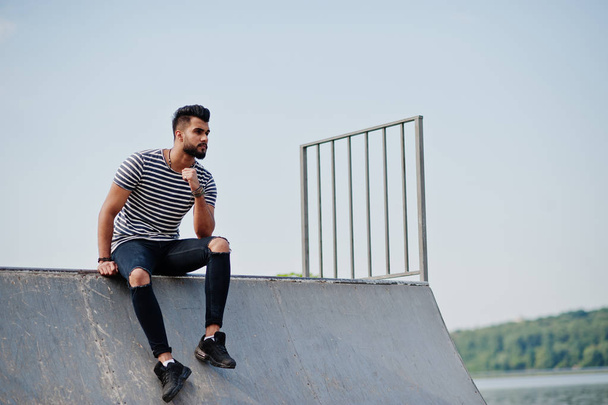 Handsome tall arabian beard man model at stripped shirt posed outdoor at skate park. Fashionable arab guy.  - Zdjęcie, obraz