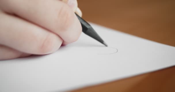 Kleine hand tekenen op blanco papier met een potlood. - Video