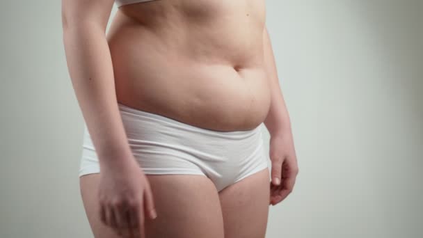 Kobieta w białej bieliźnie trzyma jej tłuszczu z brzucha. - Materiał filmowy, wideo