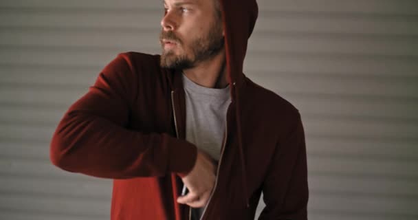 Young adult man with hooded sweatshirt using smartphone during fitness sport workout .Grunge industrial urban training.4k slow motion video - Filmmaterial, Video
