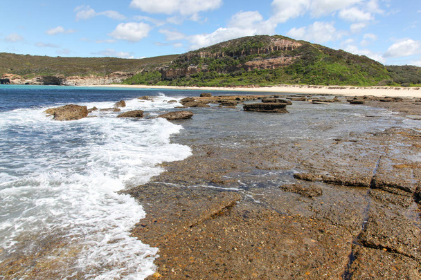 Fala toczy się po skałach przy Flat Rock na południe od Moonee - Katarzyny Hill Bay na środkowym wybrzeżu Nowej Południowej Walii. - Zdjęcie, obraz