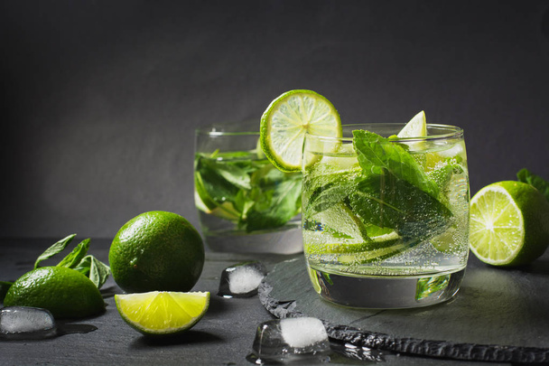 Mojito cocktail in glass with garnish on black table. Low key photo. Close up. - Fotoğraf, Görsel