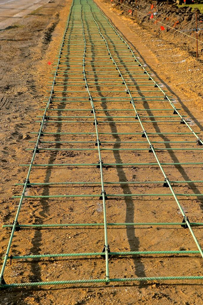 Bir gelecekteki kaldırım yapım aşamasında yerde inşaat demiri ile kum tabakası üzerinde uzunluğudur - Fotoğraf, Görsel