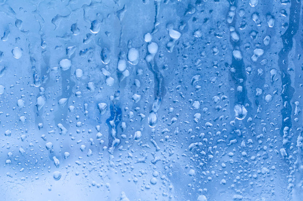 Regendruppels en bevroren water op de achtergrond van de glazen venster  - Foto, afbeelding