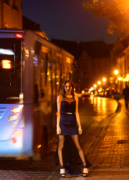 Night city with princess in celebrity style. Fashion and beauty of business lady. Sexy girl in elegant dress. Luxury woman in evening dress at night city go to prom on bus. Girl with glamour makeup. - Fotó, kép