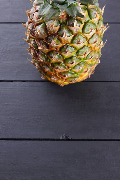 Pineapple on wooden boards, pineapple with leaves on black background, tropical fruit with copy space, blank for designer, vegetarian food, fruit for salad preparation, art - 写真・画像