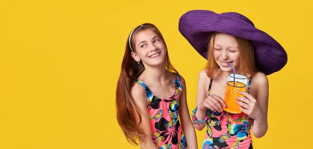 Funny children isolated yellow background,studio,blank,copy space for text,shop,advertising. Portrait two sisters friendship joy,laughing.Young girl looks aside empty space for text.Concept summer. - Fotó, kép