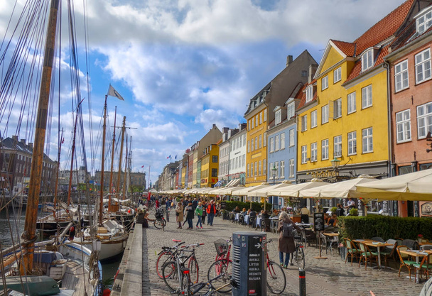 People stroll the cobblestone streets of Nyhavn area in Copenhagen Denmark - Фото, изображение