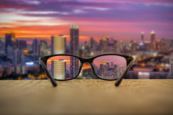 Clear cityscape focused in glasses lenses with blurred cityscape background. - Foto, Bild