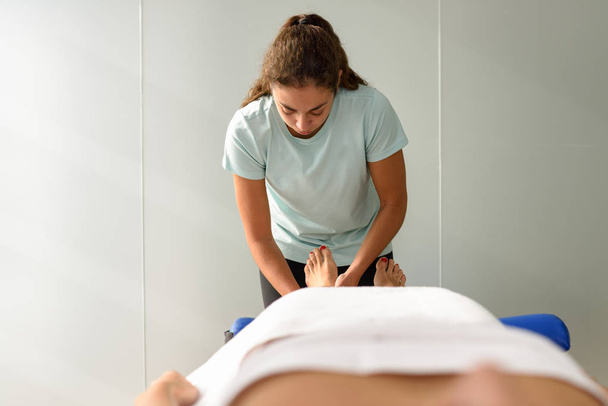 Medical massage at the foot in a physiotherapy center. Female physiotherapist inspecting her patient. - Photo, Image