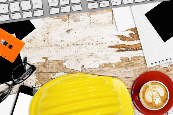 Ingénieur de bureau avec casque jaune, téléphone intelligent, tasse à café, note papier, lunettes et matériel de bureau
. - Photo, image