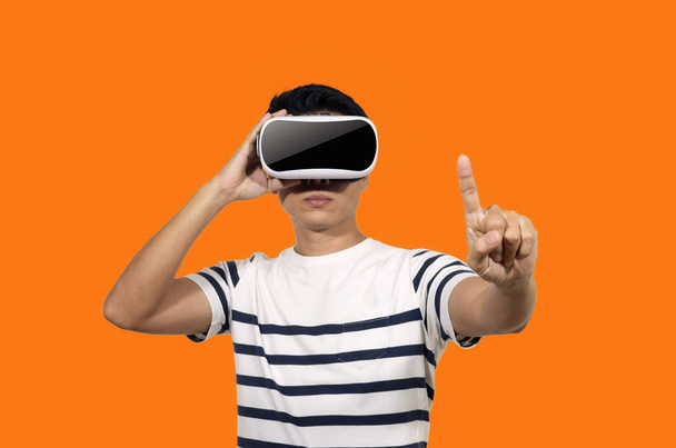 Giovane uomo con un auricolare realtà virtuale stand su sfondo arancione indoor
. - Foto, immagini