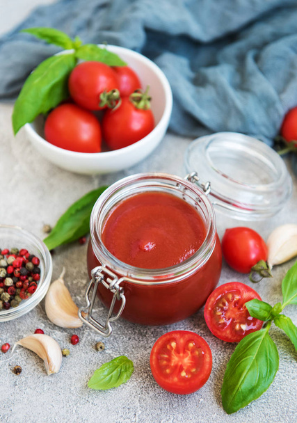 Jar met tomatensaus en ingrediënten op een stenen achtergrond - Foto, afbeelding