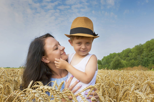 Happy family. Mom and son are laughing and talking on the wheat field. Front view. - Fotoğraf, Görsel