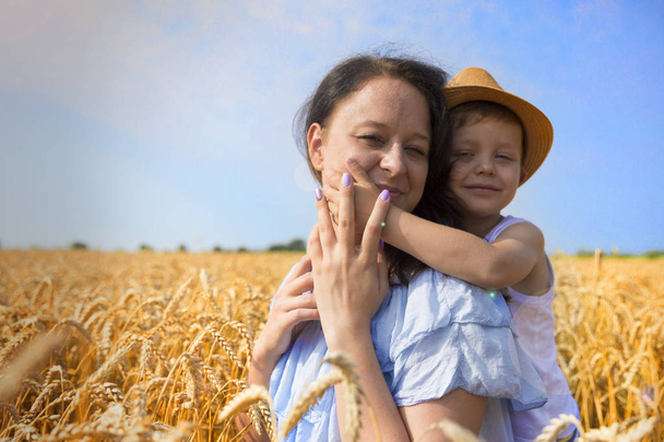 Happy family. Mom and son are laughing and talking on the wheat field. Front view. - Valokuva, kuva
