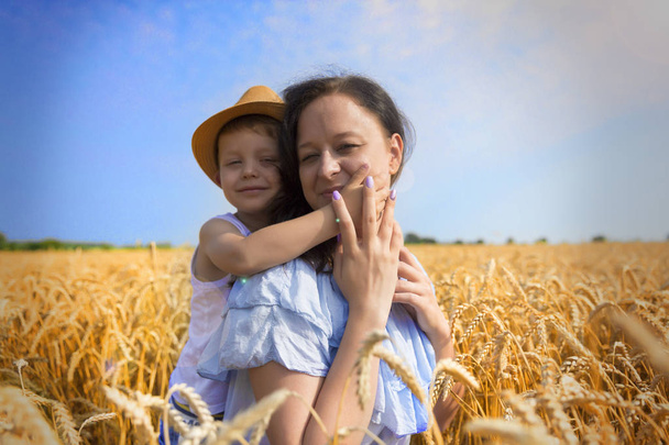 Happy family. Mom and son are laughing and talking on the wheat field. Front view. - Foto, Imagen