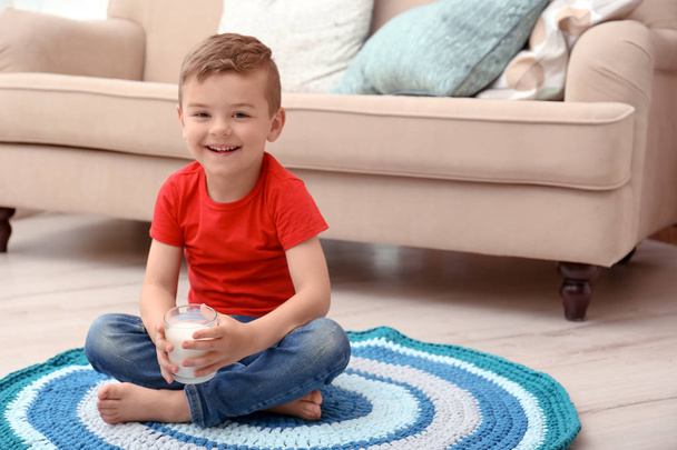 Cute little boy with glass of milk on floor at home - Фото, зображення
