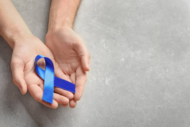 Man holding blue ribbon on grey background. Cancer awareness - Foto, afbeelding
