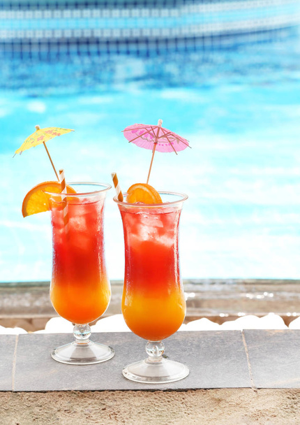 Glasses with tasty cocktails near swimming pool - Фото, зображення