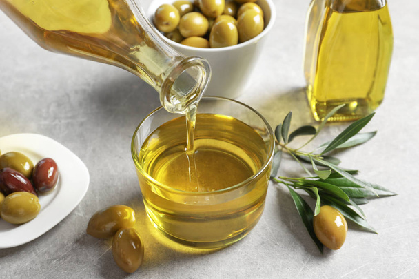 Verser de l'huile d'olive fraîche dans du verre sur la table
 - Photo, image