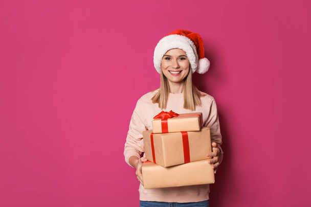 Young woman with Christmas gifts on color background - Fotografie, Obrázek