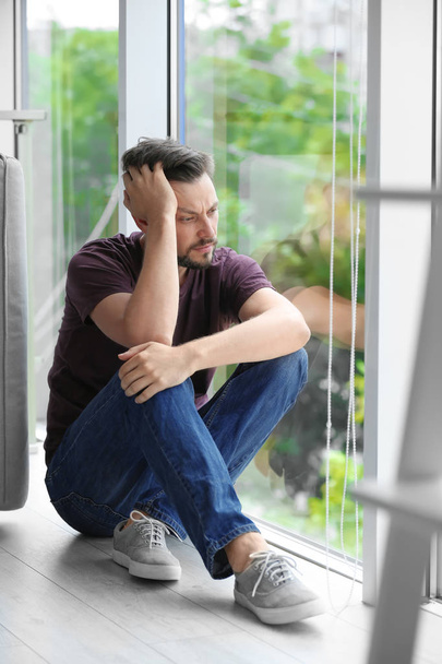 Lonely depressed man near window at home - Photo, Image