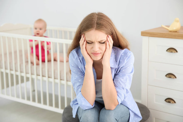 Young mother suffering from postnatal depression and little baby in room - Valokuva, kuva