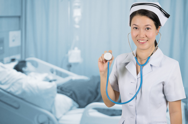 Asyalı hemşire arka plan üzerinde stetoskop ile bulanıklık hasta odası. - Fotoğraf, Görsel