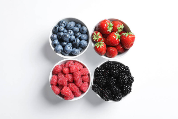 Bowls with raspberries and different berries on white background - Fotó, kép