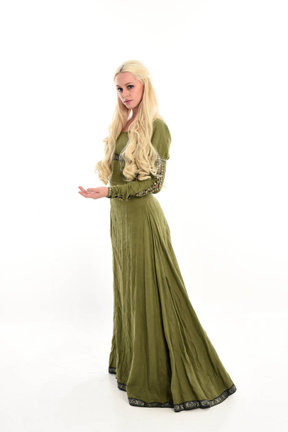 Ολόσωμο πορτρέτο του κοπέλα φορώντας πράσινα μεσαιωνικό φόρεμα, όρθια στάση στο προφίλ πλευρά. απομονωμένα σε φόντο λευκό στούντιο. - Φωτογραφία, εικόνα