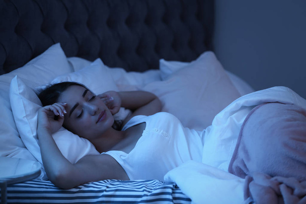 Fiatal nő alszik az ágyban éjjel. Alvási idő - Fotó, kép