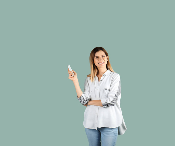 Frau mit Klimaanlage Fernbedienung auf farbigem Hintergrund - Foto, Bild