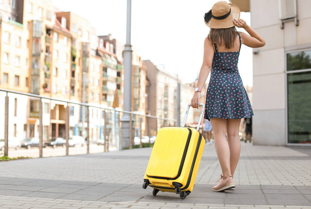 Young woman with yellow carry on suitcase outdoors - Photo, Image