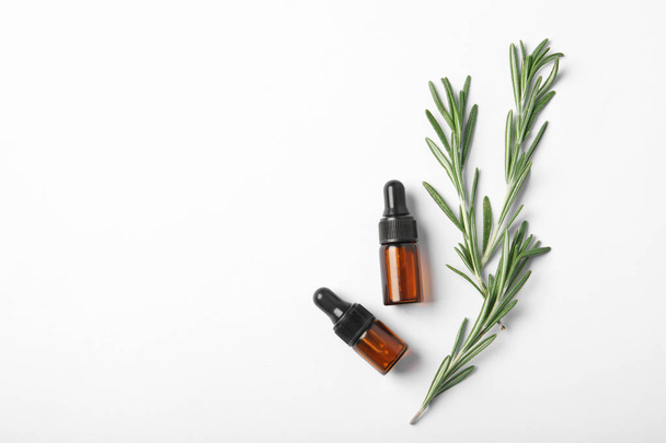 Bottles of rosemary oil and fresh twigs on white background, top view - Foto, Bild