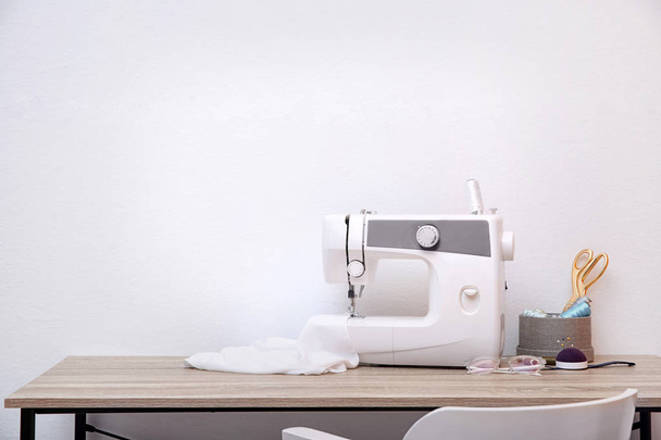 Sewing machine on table against light background - Fotó, kép