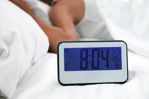 Digital alarm clock and sleepy woman in bed. Time of day - Foto, Imagen