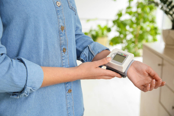 Young woman checking pulse with blood pressure monitor on wrist, closeup - Φωτογραφία, εικόνα