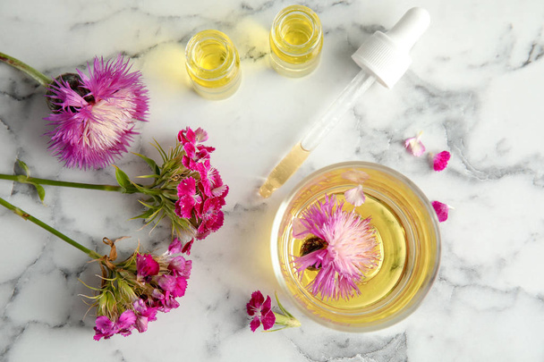 Flat lay composition with essential oils and flowers on marble background - Foto, Bild