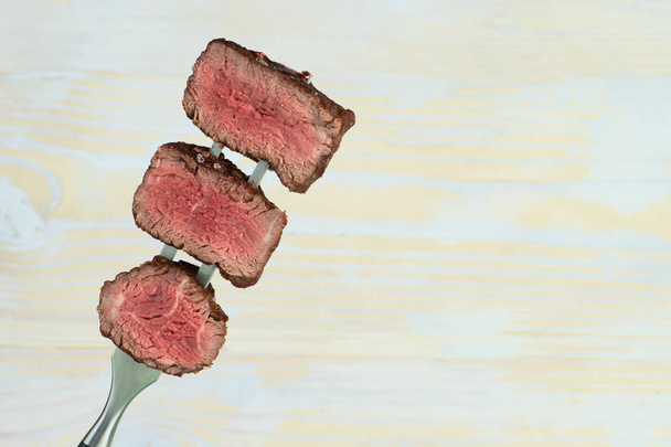 sliced steaks impaled on meat fork - Φωτογραφία, εικόνα
