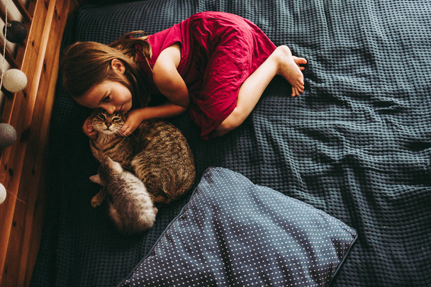 7 years little  girl paying with the kittens on bed - Zdjęcie, obraz