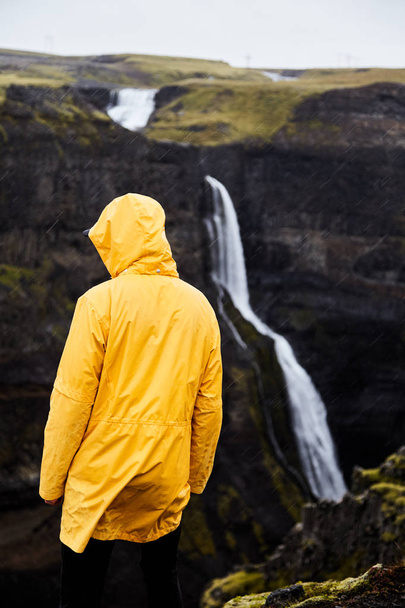 Cascada Haifoss en Islandia. Un joven se para en un acantilado y mira la cascada
.  - Foto, imagen