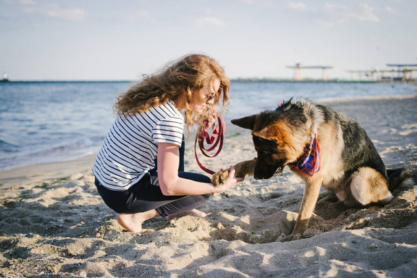 トレーニングとビーチで彼女のジャーマン ・ シェパード犬を屋外で遊ぶ若い女性 - 写真・画像
