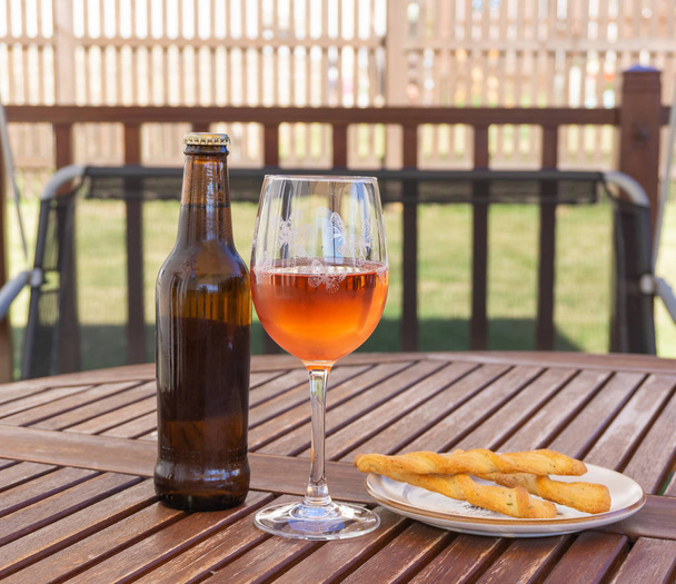 Bier-Rosenwein und ein paar Stockbrot auf einem Gartentisch an einem sehr heißen Sommertag. - Foto, Bild